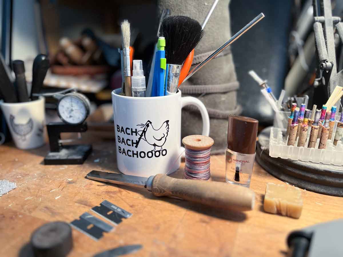 white ceramic mug with chicken holding an oboe and the saying "Bach Bach bachooooo" on a reed making desk with reed making accessories knives and tools surrounding it