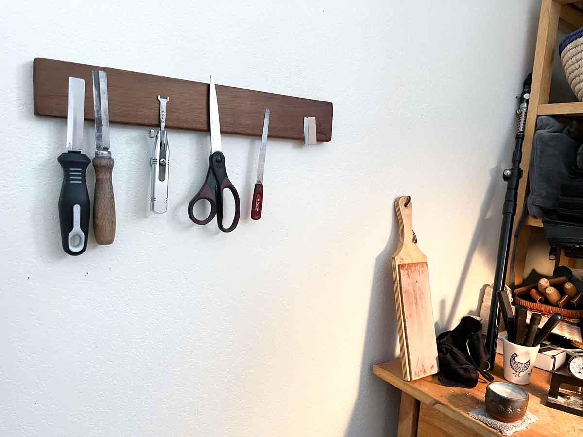 Image of a magnetic strip on a white wall with oboe reed accessory and tools hanging off of it.